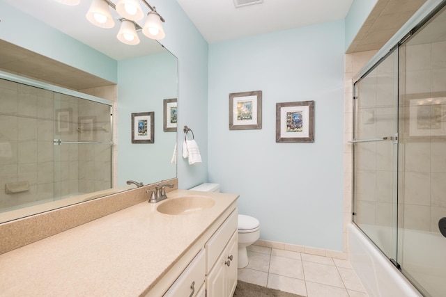 full bathroom with vanity, bath / shower combo with glass door, toilet, and tile patterned floors