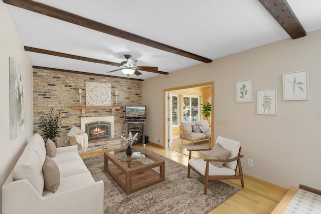 living room with ceiling fan, beam ceiling, a fireplace, and hardwood / wood-style floors