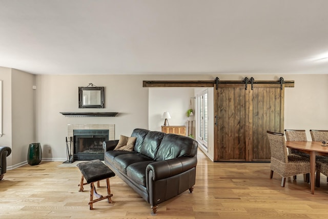 living room featuring a barn door, a tile fireplace, and light hardwood / wood-style flooring