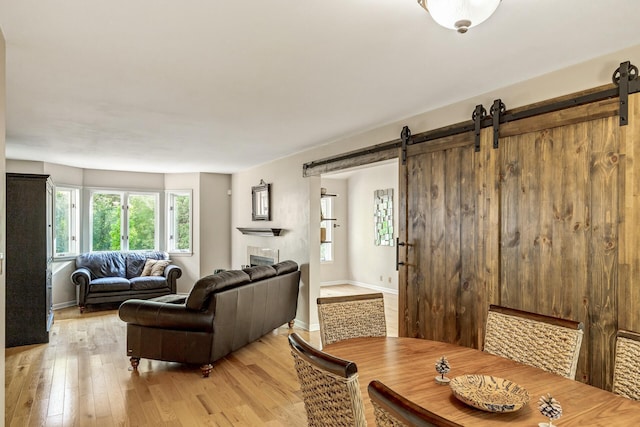 dining room with a barn door and light hardwood / wood-style flooring