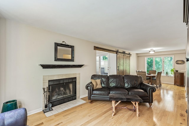 living room with light hardwood / wood-style flooring, plenty of natural light, and a tiled fireplace