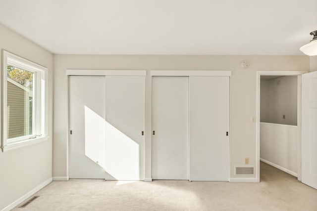 unfurnished bedroom featuring two closets and light colored carpet