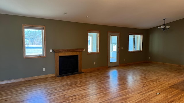 unfurnished living room with lofted ceiling, light wood-type flooring, and an inviting chandelier