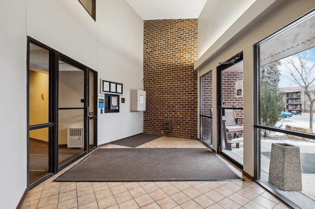 corridor with a high ceiling, brick wall, and light tile patterned floors