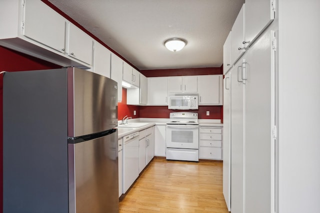 kitchen with sink, white cabinets, white appliances, and light hardwood / wood-style flooring