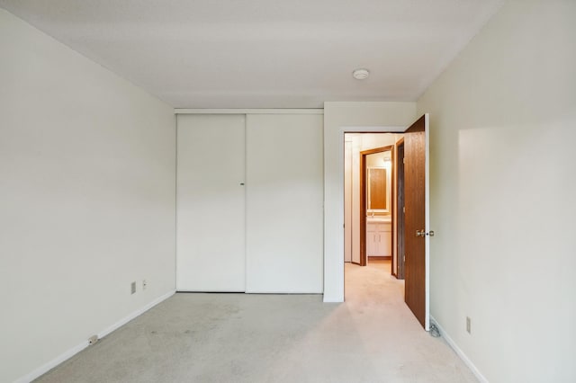 unfurnished bedroom with light colored carpet and a closet