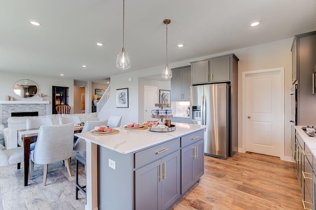 kitchen with hanging light fixtures, gray cabinets, stainless steel fridge, a fireplace, and a kitchen island