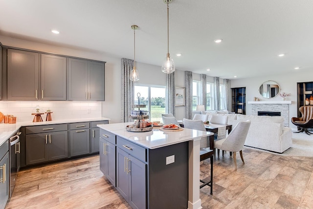 kitchen with tasteful backsplash, gray cabinetry, pendant lighting, a fireplace, and a kitchen island