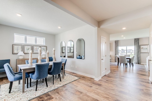 dining space with beamed ceiling, light hardwood / wood-style flooring, and a wealth of natural light