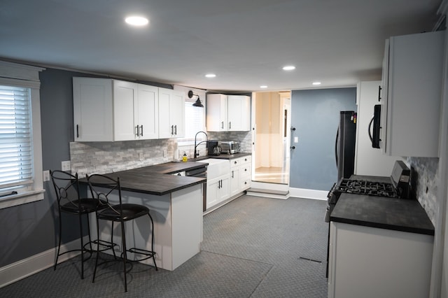 kitchen with appliances with stainless steel finishes, a breakfast bar area, white cabinetry, and kitchen peninsula