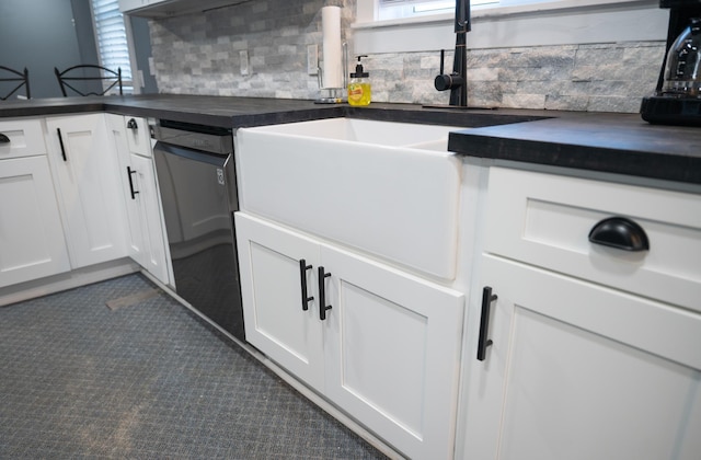 kitchen featuring sink, white cabinets, dark tile patterned flooring, and black dishwasher