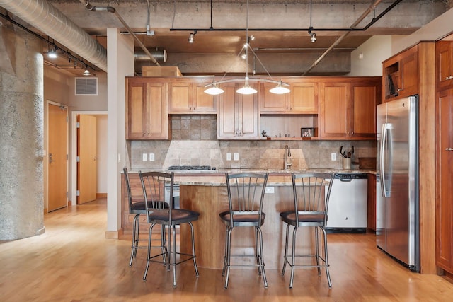 kitchen with light stone countertops, light hardwood / wood-style flooring, stainless steel appliances, and track lighting