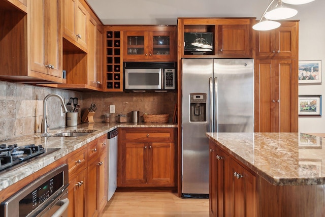 kitchen featuring pendant lighting, sink, tasteful backsplash, light stone counters, and stainless steel appliances