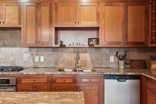 kitchen featuring decorative backsplash, sink, light stone counters, and appliances with stainless steel finishes