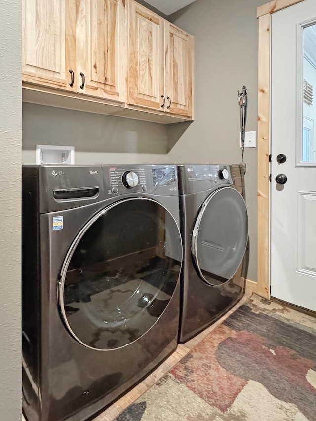 laundry area with tile patterned flooring, separate washer and dryer, and cabinets