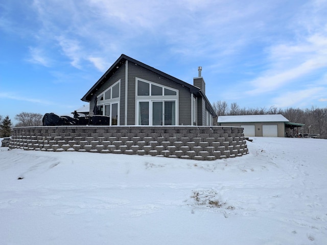 snow covered property featuring a garage and an outbuilding