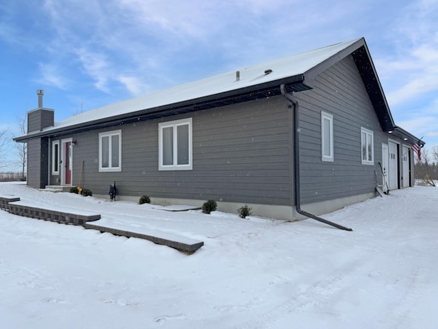 snow covered rear of property with a garage