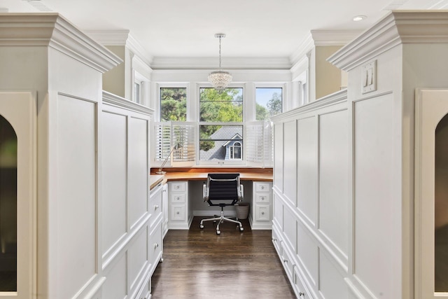 home office featuring an inviting chandelier, built in desk, crown molding, and dark hardwood / wood-style floors