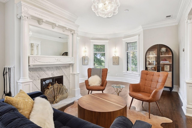 sitting room featuring dark wood-type flooring, crown molding, a fireplace, and ornate columns