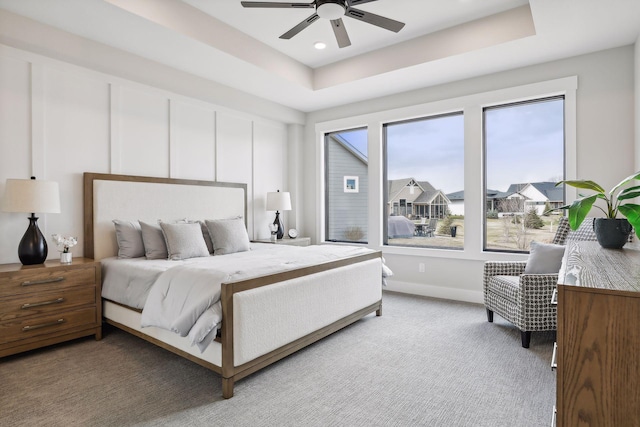 bedroom featuring ceiling fan, carpet flooring, and a tray ceiling