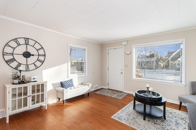 sitting room with plenty of natural light, crown molding, and wood-type flooring