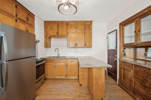 kitchen featuring sink, appliances with stainless steel finishes, light stone counters, and light hardwood / wood-style flooring