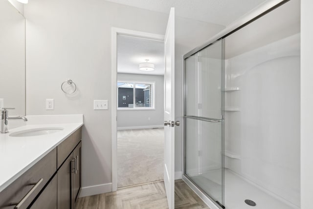 bathroom featuring a shower with door, vanity, parquet flooring, and a textured ceiling