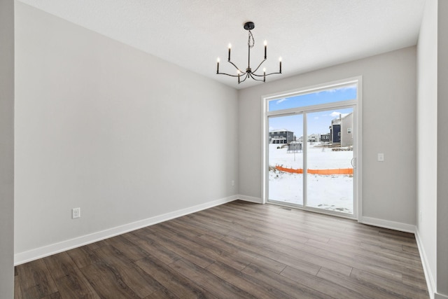 unfurnished dining area featuring dark hardwood / wood-style floors, a textured ceiling, and a chandelier