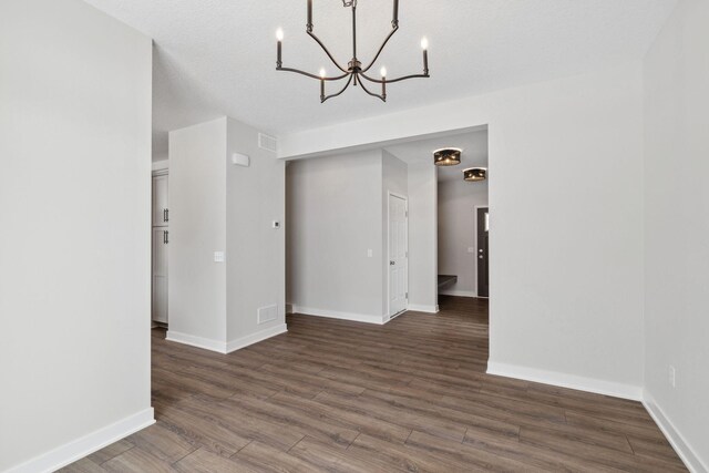 unfurnished room featuring dark hardwood / wood-style flooring and a notable chandelier