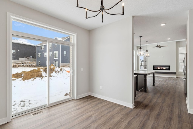 dining room featuring hardwood / wood-style flooring, ceiling fan with notable chandelier, and a textured ceiling