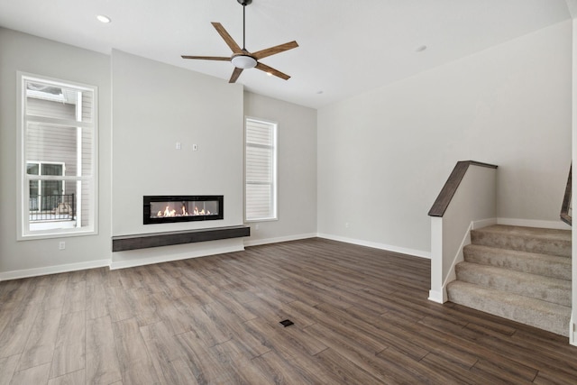 unfurnished living room with ceiling fan, plenty of natural light, and dark hardwood / wood-style floors