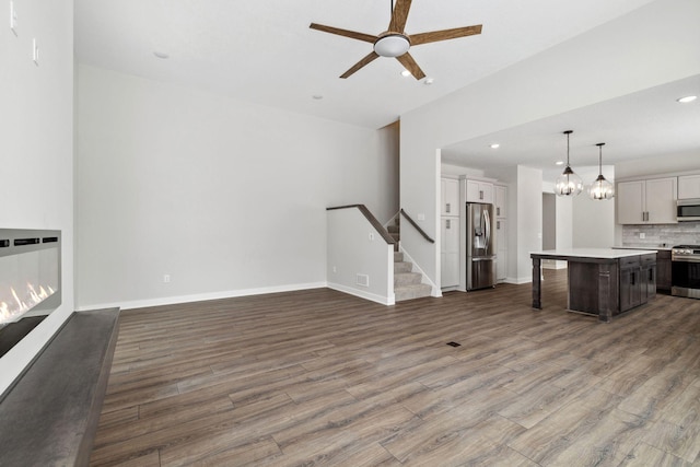 unfurnished living room featuring ceiling fan and dark hardwood / wood-style flooring