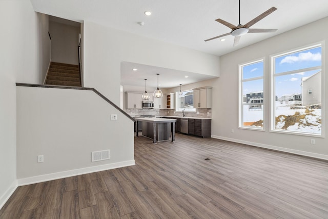 unfurnished living room featuring hardwood / wood-style floors, sink, and ceiling fan