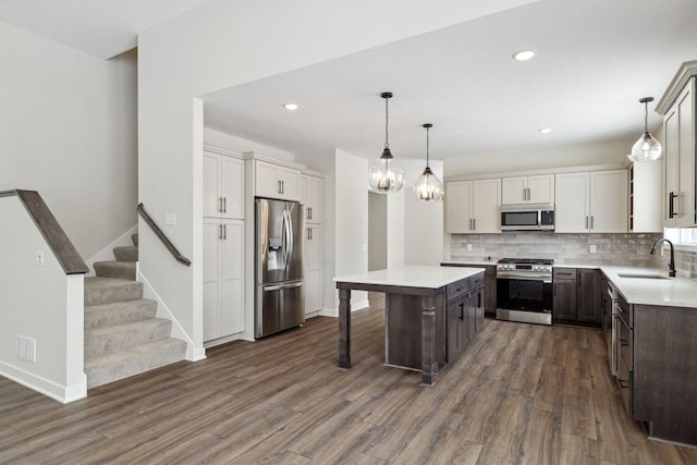 kitchen featuring stainless steel appliances, decorative light fixtures, sink, and a kitchen island