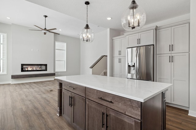 kitchen with dark wood-type flooring, decorative light fixtures, stainless steel fridge, and a healthy amount of sunlight