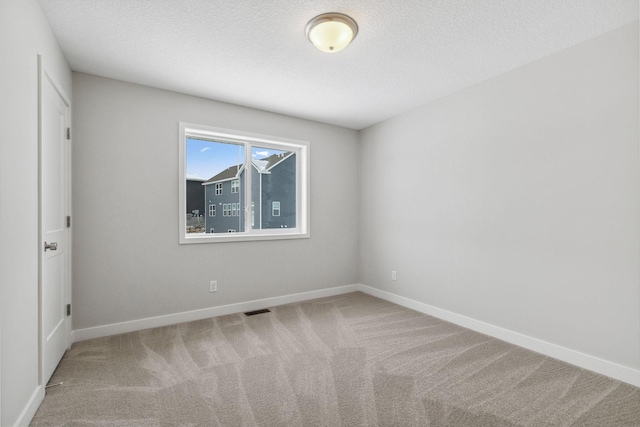 unfurnished room featuring light colored carpet and a textured ceiling