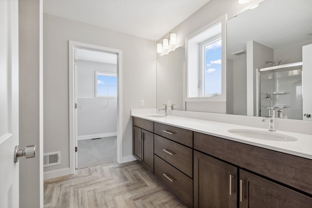 bathroom featuring vanity, parquet flooring, a textured ceiling, and walk in shower