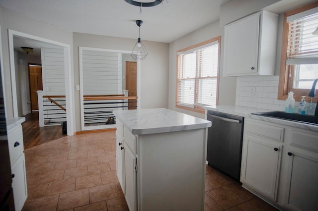 kitchen with white cabinetry, stainless steel dishwasher, backsplash, hanging light fixtures, and a kitchen island