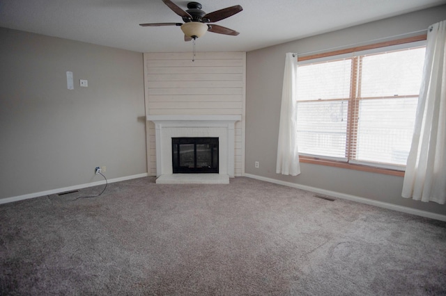 unfurnished living room featuring ceiling fan, a brick fireplace, and carpet floors