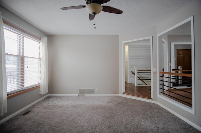 carpeted spare room featuring a textured ceiling and ceiling fan