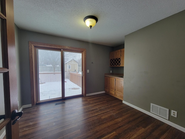 unfurnished dining area with a textured ceiling and dark hardwood / wood-style flooring