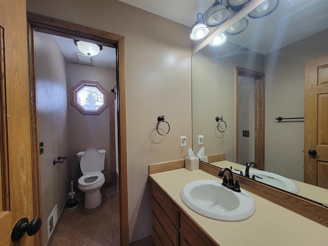 bathroom with toilet, vanity, and tile patterned flooring