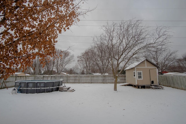 yard layered in snow featuring an outbuilding and a fenced in pool