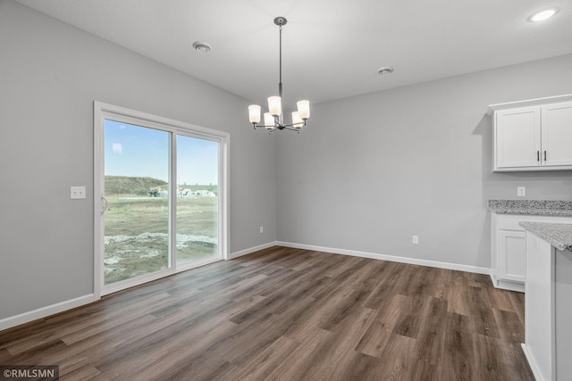 unfurnished dining area with a notable chandelier and dark hardwood / wood-style floors