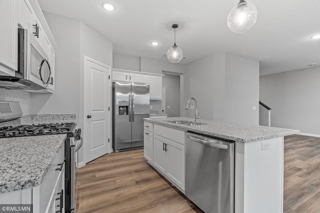 kitchen featuring an island with sink, white cabinetry, appliances with stainless steel finishes, and hanging light fixtures