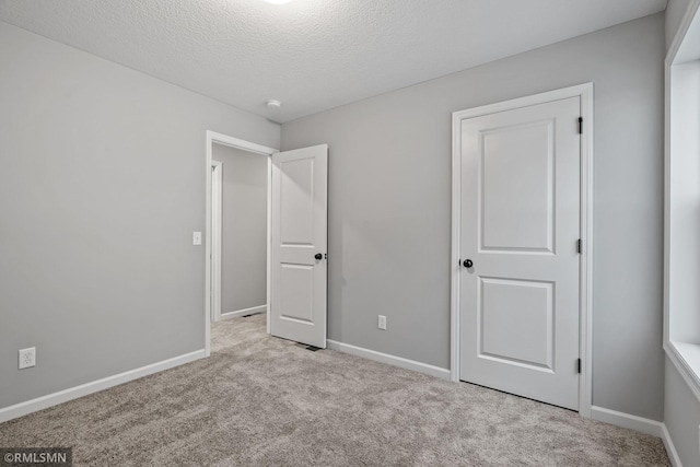 unfurnished bedroom featuring light carpet and a textured ceiling