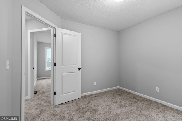 empty room with light colored carpet and a textured ceiling