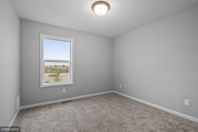 carpeted empty room featuring a textured ceiling