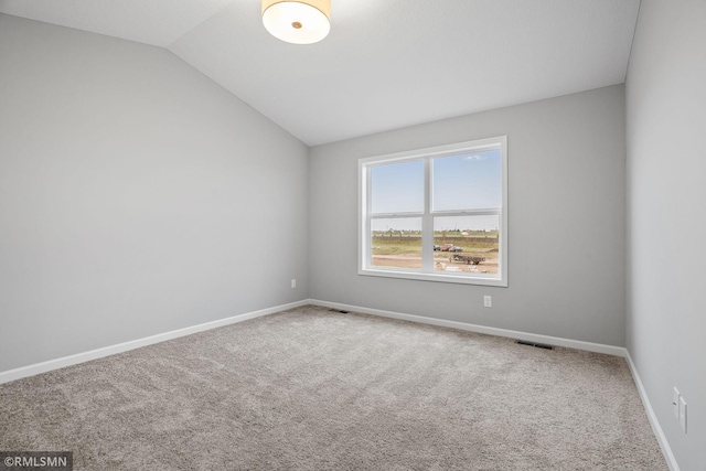 carpeted spare room featuring lofted ceiling