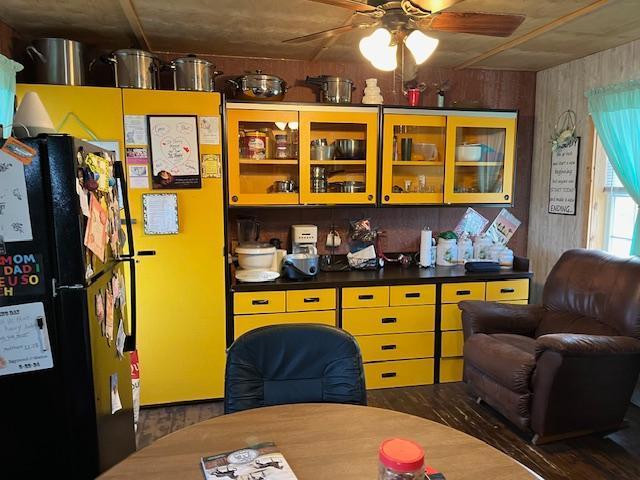 kitchen featuring ceiling fan, black fridge, and wooden walls